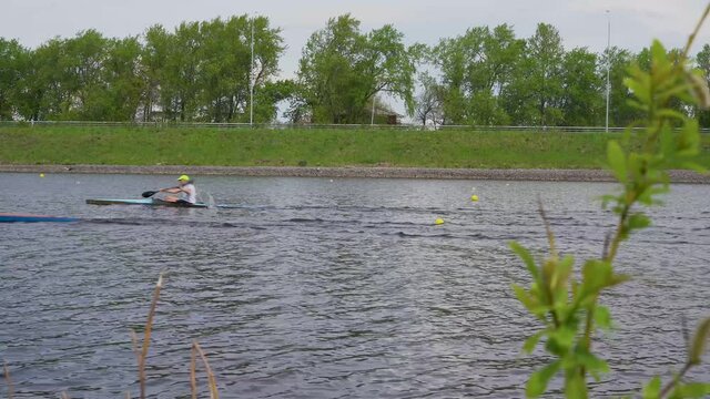 Kayak athletes compete with each other on the river in sunny weather in calm water. 4K video.