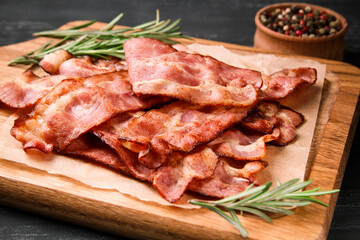Hot fried bacon with rosemary on a black background.