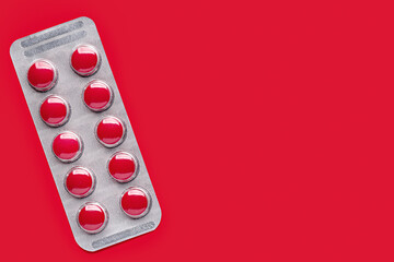 Red pills in a package, close-up. Studio shot, copy space, red background.