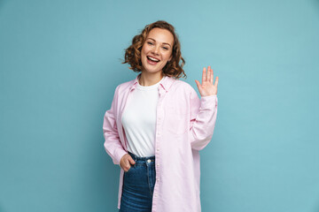 Young ginger woman with wavy hair gesturing and smiling at camera