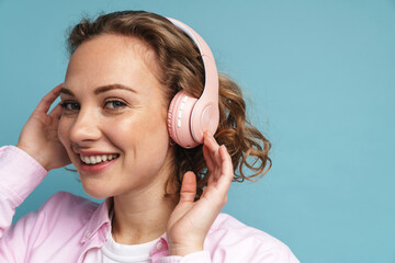 Young ginger woman laughing while listening music with headphones