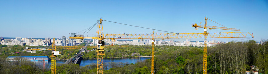 Fototapeta premium Panoramic view cityscape of the left bank of the Dnieper with concstruction cranes, Kiev, Ukraine.