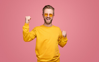 Cheerful hipster celebrating victory with clenched fists