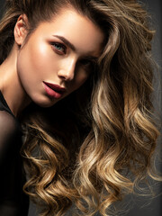 Portrait of a  beautiful woman with a long hair. Pretty blonde girl with curly hairstyle.