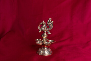 Indian traditional bronze oil lamp in the form of a bird on the background of a dark red sari. Metal diya. traditional Indian religious ceremony of Hindus. Diwali