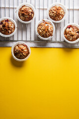 homemade muffins on a baking rack on a yellow background. place for your text, flat lay