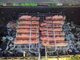 fried bbq sausages on the grill under hot coals top view