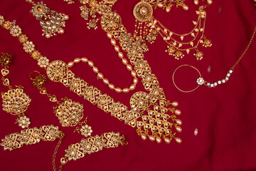 Indian traditional gold Indian wedding women's jewelry on red saree background. Close-up. Still-life.