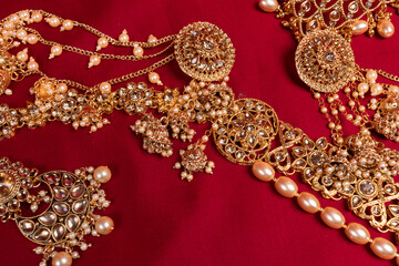 Indian traditional gold Indian wedding women's jewelry on red saree background. Close-up. Still-life.