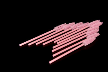 Pink eyelash brushes on a black background. Cosmetic accessories for eyelash extensions