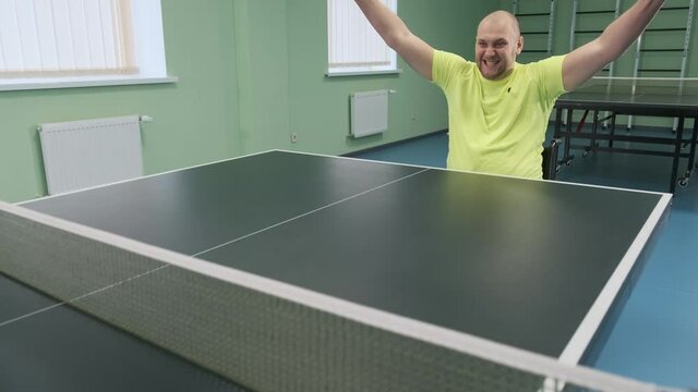 A man in a wheelchair plays ping pong. People with disabilities play table tennis. Rehabilitation of the disabled. Sport.