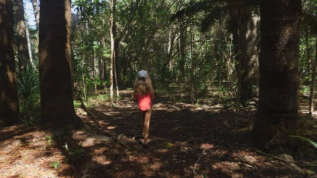 Young girl in bathing suit explores jungle in New Caledonia.