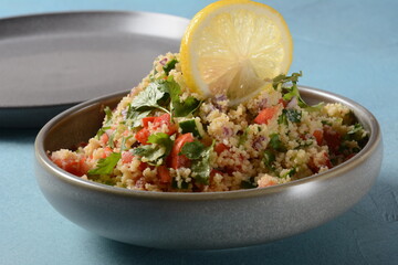 Tabbouleh - a Middle Eastern cuisine vegetarian salad with chopped parsley, tomatoes, mint, onion and bulgur, and seasoned with olive oil, lemon juice.