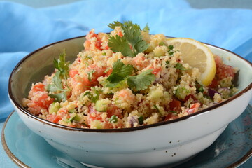 Tabbouleh - a Middle Eastern cuisine vegetarian salad with chopped parsley, tomatoes, mint, onion and bulgur, and seasoned with olive oil, lemon juice.