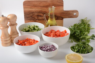White bowls with grated vegetables of different colors. Cooking board with Ingredients ready for the salad.