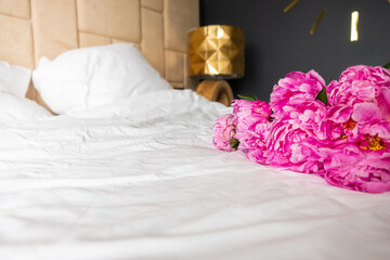Beautiful big pink peonies lying on the bed. Fresh spring flowers. Copy space for text.