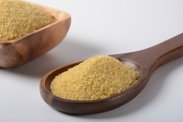 Uncooked bulgur in wooden bowl on white table background, rustic style. Bulgur wheat grains