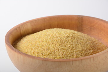 Uncooked bulgur in wooden bowl on white table background, rustic style. Bulgur wheat grains