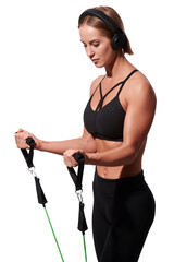 Strong muscular sportswoman in headphones exercising with resistance band over white isolated background