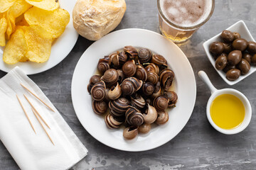 Fototapeta premium boiled snails with bear, bread, olives and potato chips on blue
