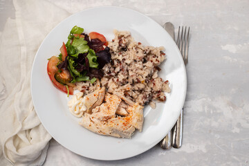 chicken breast with boiled rice and salad on white plate