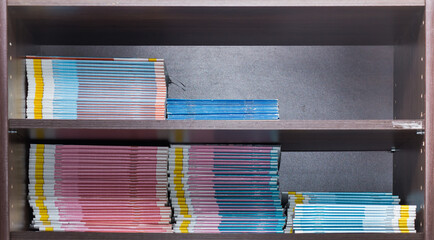 Bookshelf with textbooks and notebooks neatly arranged on the shelf. Shelving in the classroom of the school. Teaching and methodological aids for working in the classroom for teachers and students.