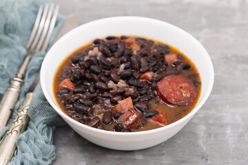 black beans with meat and sausages in white bowl