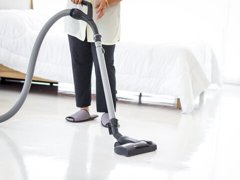 Asian senior elderly woman housewife vacuuming the floor at bedroom with vacuum cleaner, grandma doing housework at house.