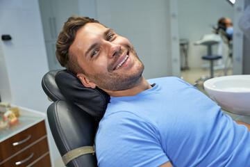 Joyous patient of dental clinic resting in dental chair