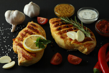 Grilled chicken meat and ingredients on black background, close up