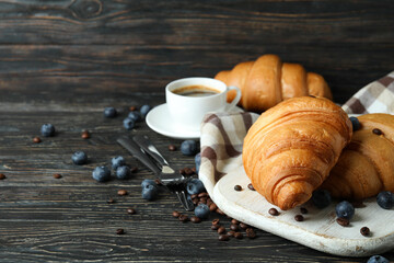 Concept of tasty breakfast with croissants on wooden background