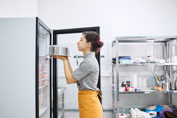 A bright pastry chef puts the finished cake in the refrigerator