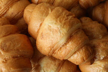 Fresh tasty croissants on whole background, close up