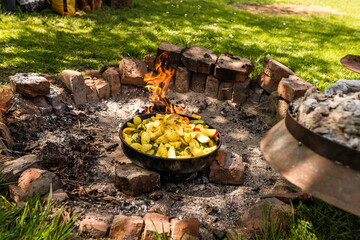 Cooking traditional dalmatian, croatian, bosnian dish called peka. Meat, potatoes and vegetables in...