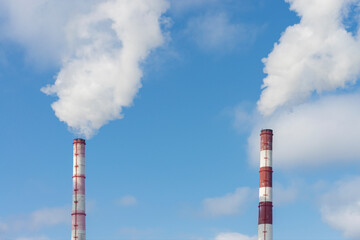 Two pipes and smoke from them against the blue sky. Industrial landscape. Front and bottom view.