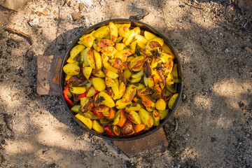 Cooking traditional dalmatian, croatian, bosnian dish called peka. Meat, potatoes and vegetables in pot and covered with hot charcoal and ash. Balkan food.