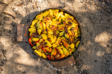 Cooking traditional dalmatian, croatian, bosnian dish called peka. Meat, potatoes and vegetables in pot and covered with hot charcoal and ash. Balkan food.