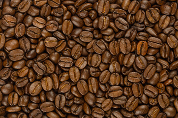 Roasted coffee beans, background, from above. Dark brown, roasted seeds of berries from Coffea...
