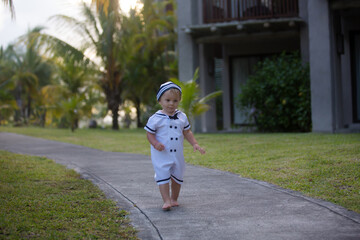 Fototapeta na wymiar Beautiful toddler boy, dressed as a sailor, playing on the beach on sunset, enjoying tropical magical holiday vacation