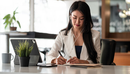 Businesswoman with earbuds for video conference lecture note.woman using tablet webinar video course at home office