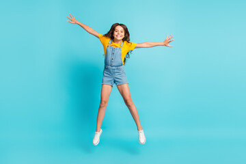 Fototapeta na wymiar Full length photo of funny charming small schoolgirl dressed yellow t-shirt jumping high like star isolated blue color background