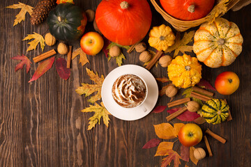 Autumn composition with cup of coffee, pumpkins, apples, nuts and cinnamons on dark rustic wooden background.