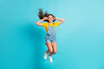 Full length photo of charming cute small school girl wear denim jeans overall jumping v-signs cover...