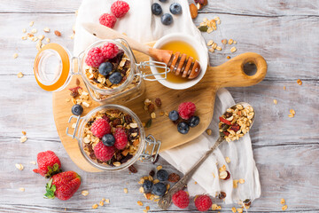 Handmade muesli granola with fresh berries, honey, seeds in glass jars
