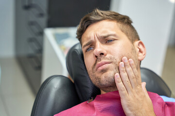 Brunette man suffering from dental pain in clinic