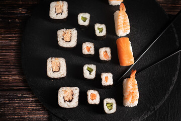 Sushi sind aufgelegt auf der schwarzen Platte Schwarze Stäbe fassen ein Sushi an. Sehr gut...