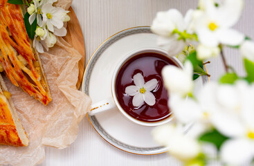 A cup of black tea in white apple blossoms