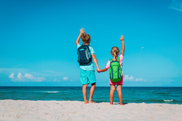 happy ravel on beach, boy and girls with backpack at sea