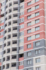 Residential high-rise new building in a residential area of the city. Building with windows and balconies. Modern new buildings, building facades. Real estate and urban architecture concept.
