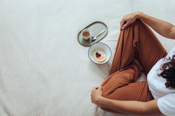 Frau im Schneidersitz mit Tee und Frühstück im Bett